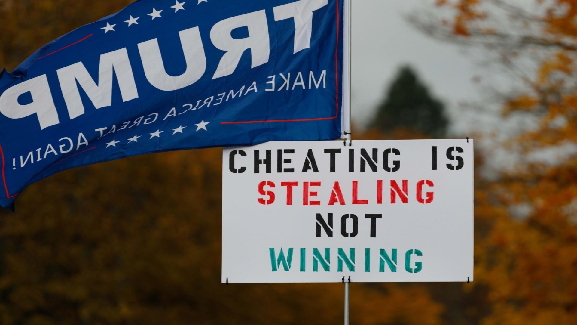 A photo shows a Trump flag flying next to a sign that reads, ''Cheating is stealing, not winning.''