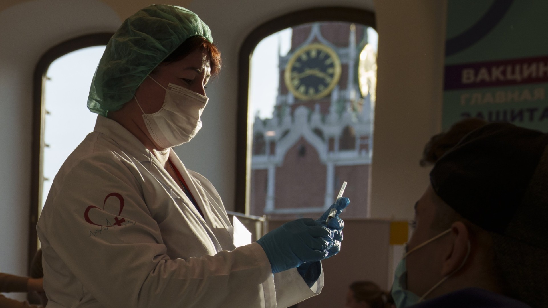 Rusya'da arkada ikonik Ortodoks mimarisi gölgesinde Covid-19 aşısı yapmaya hazırlanan bir hemşire. NBC, 2021.